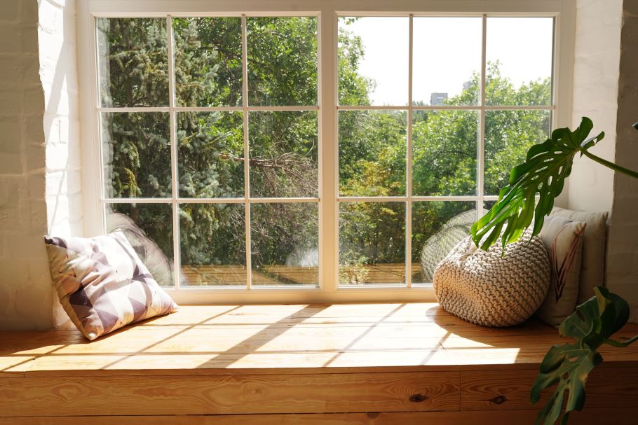 Fenster mit hölzerner Sitz-Fensterbank. Auf der Fensterbank Kissen.