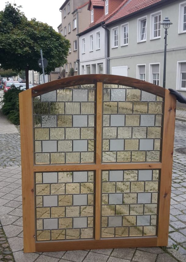 Hölzernes Bleiglasfenster mit durchsichtigen und gelblichen Elementen, oben abgerundet